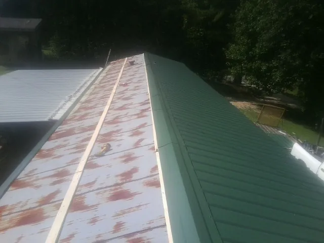 Old rusted panels beside newly installed green metal roofing — Wind Damage Roof Repair by Roofing Brothers in North Palm Beach