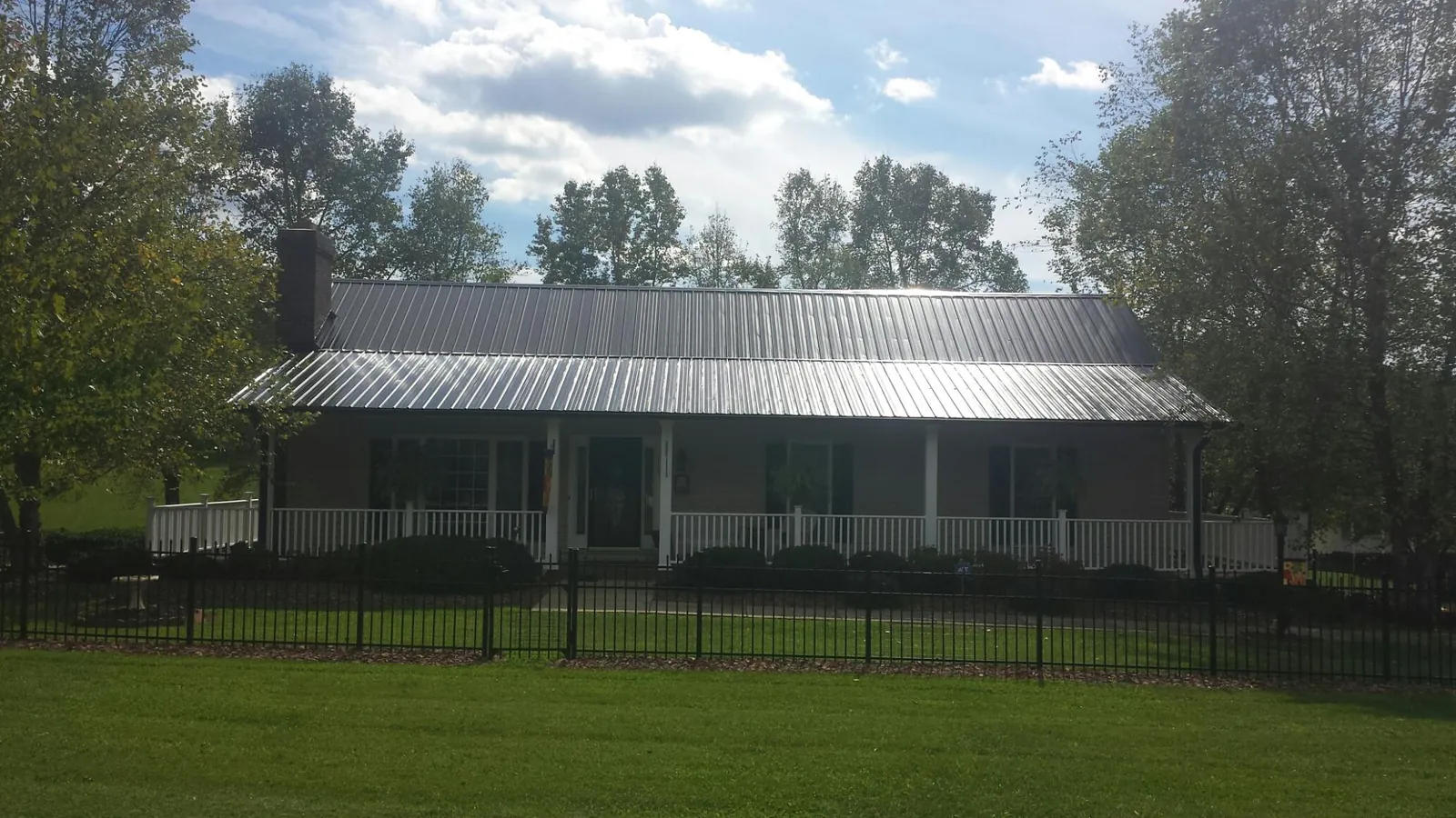 Gray metal roof on a brick ranch with a full width front porch — Gutter Guard Installation work by our crew in North Palm Beach