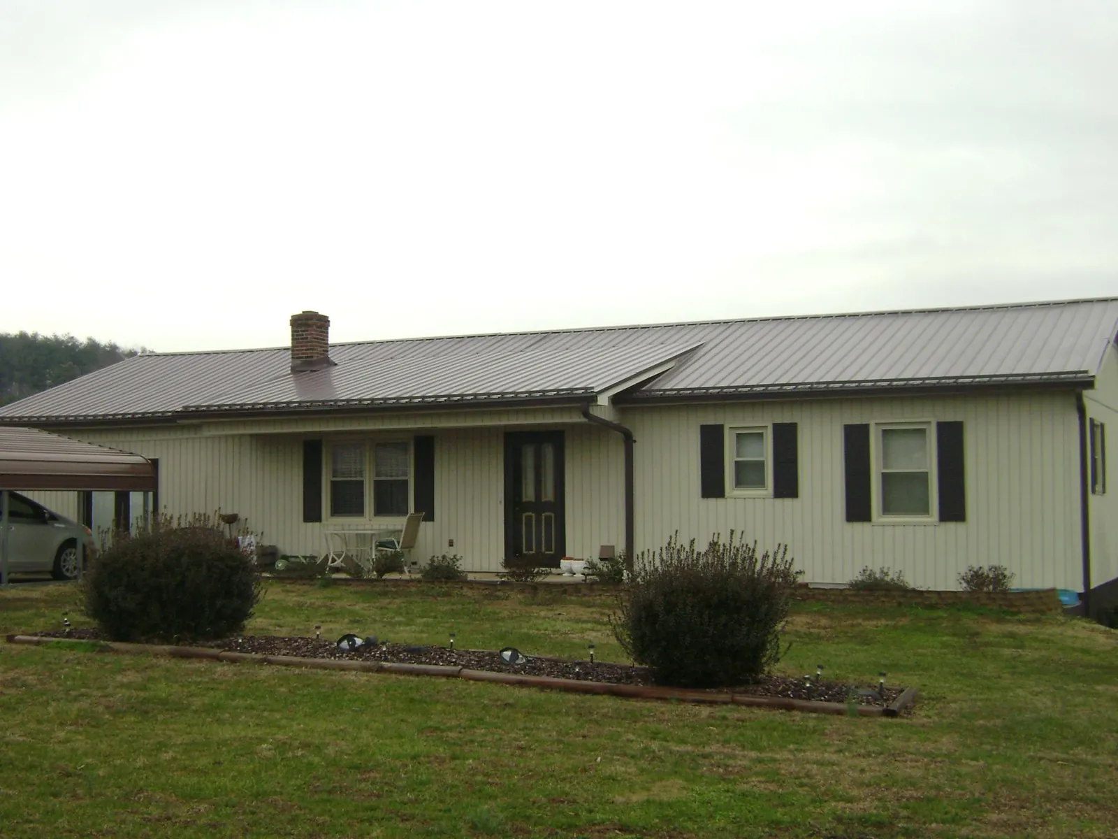 Brown metal roof on a cream sided ranch home with a brick chimney in North Palm Beach