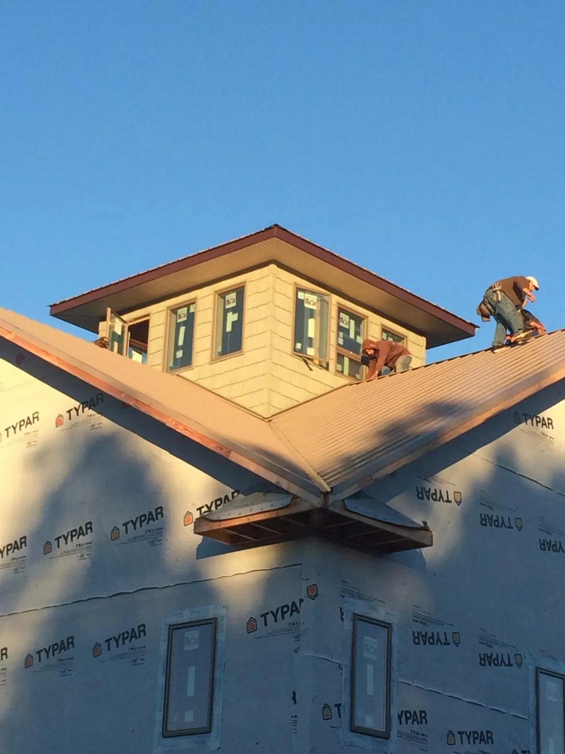 Roofers working around a rooftop cupola on a new metal roof at sunset — Roof Waterproofing in North Palm Beach by Roofing Brothers